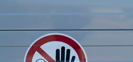 Circular red no-touch sign on a gray surface, showing a raised hand in front of a small figure—do not touch.