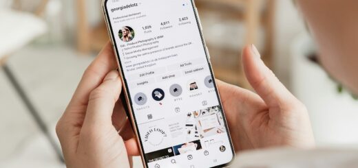Close-up of a person holding a smartphone displaying an Instagram profile page (username georgiadelotz) with a grid of circular story icons and posts visible.